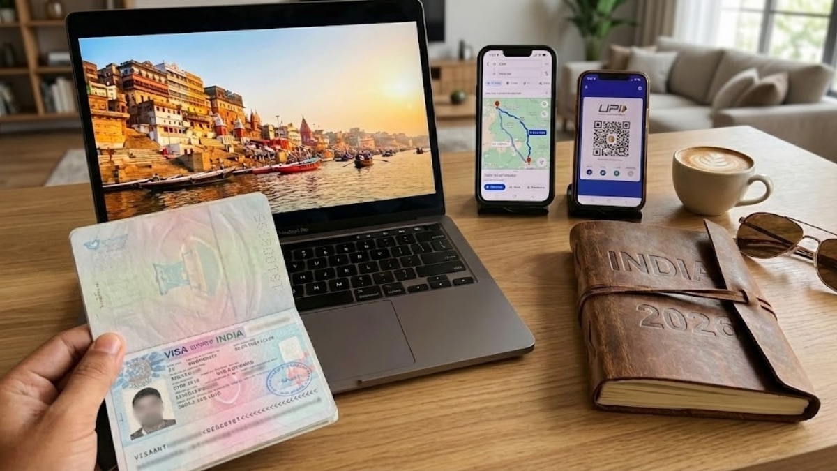 Flat lay of travel planning essentials for India including passport with visa, smartphone with route map, UPI payment app, and laptop showing Varanasi Ghats