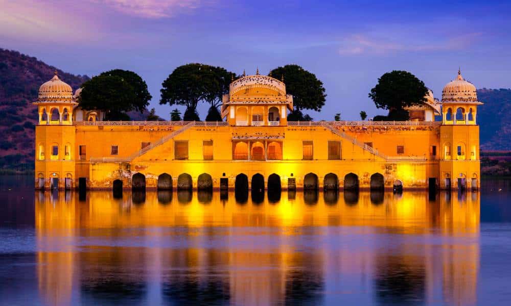 Jal Mahal lights reflect on the water in the evening. While it looks like a single-story building floating on Man Sagar Lake, it is actually five stories tall. Four of those stories stay submerged underwater. Jaipur City Guide recommends evening view.