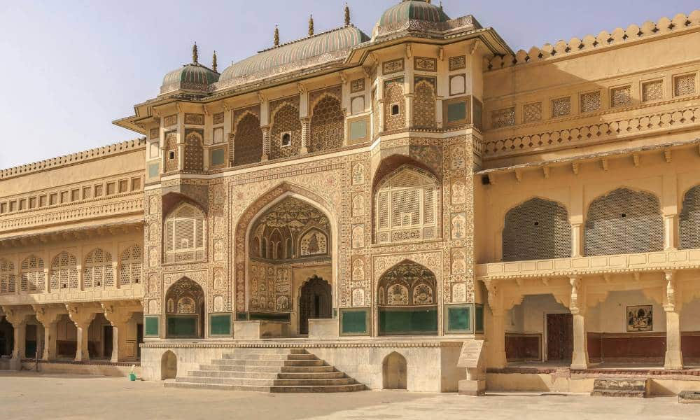 A detailed shot of the grand Ganesh Pol gateway at Amber Fort, featuring colorful vegetable-dye frescoes and lattice windows.