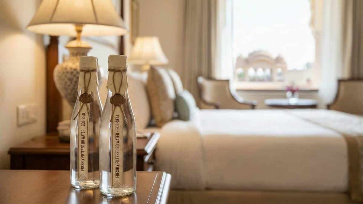 Two elegant glass water bottles with paper seals on a hotel bedside table.