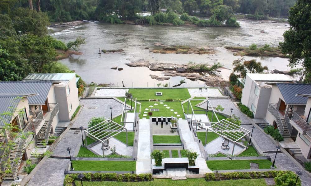 Niraamaya Retreats Samroha Athirappilly outdoor area overlooking waterfall stream.